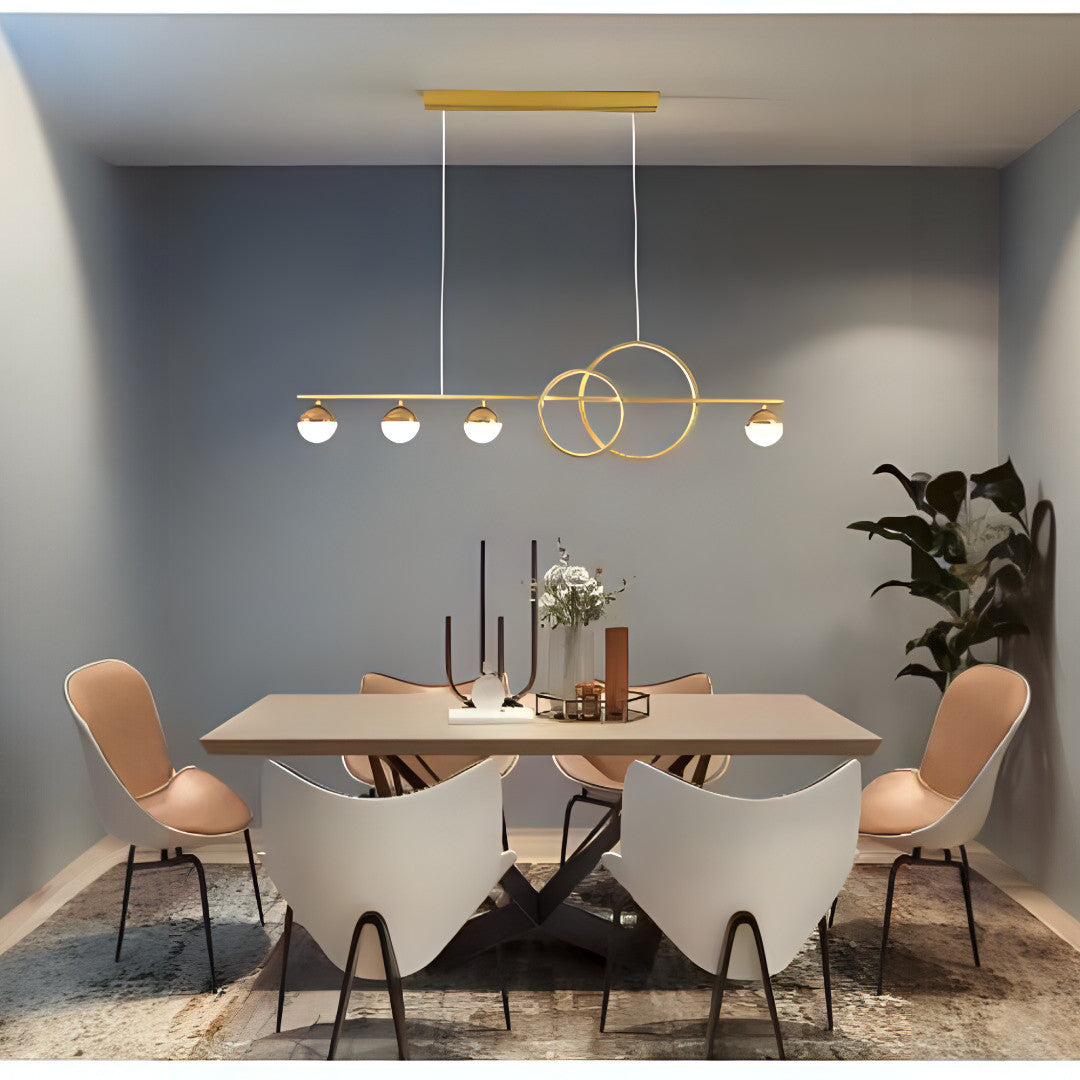 A dining room featuring a sleek gold linear chandelier with circular and spherical lighting elements.