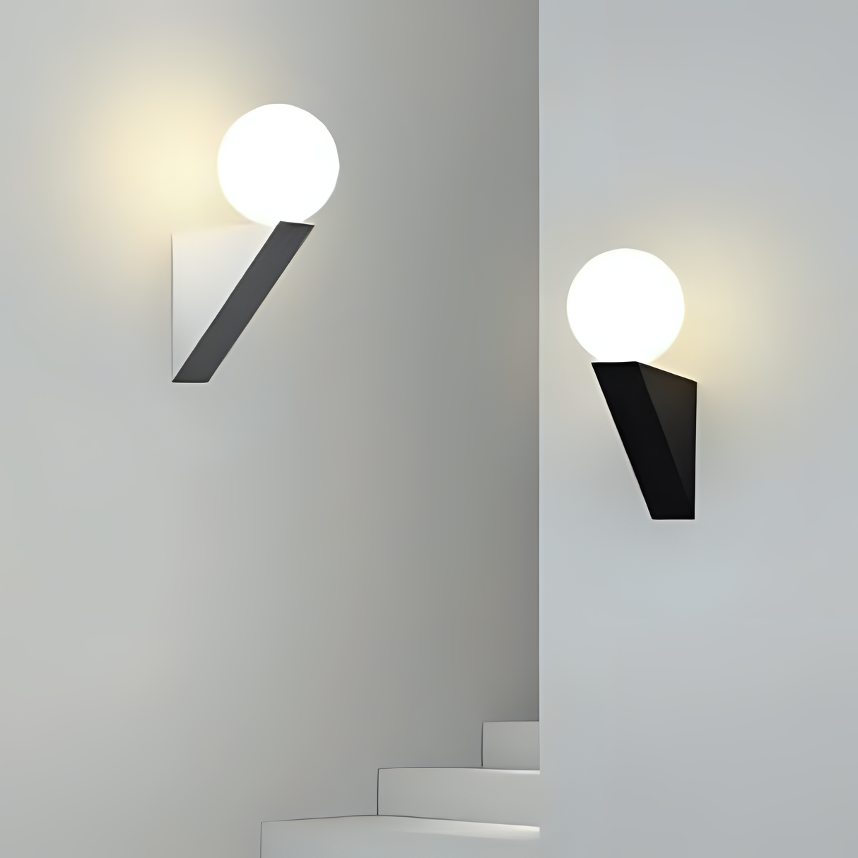 A pair of geometric black and white sconces with spherical bulbs, mounted on a light-colored wall.