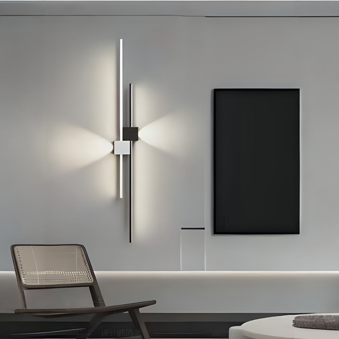 A minimalist vertical wall light with two slim LED strips forming a cross pattern, installed in a modern living room.