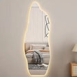 Oval-shaped mirror with LED lighting in a room with a sofa and lamp.