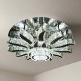 A grand round chandelier with multiple outward-bending arms made of clear crystal, forming a radial pattern and suspended from a dark ceiling; it gives off cool white lighting and adds dramatic flair to large spaces.
