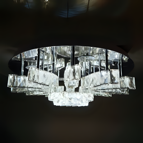 A rectangular crystal chandelier with a mirror base and rows of hanging clear glass prisms, suspended from a dark ceiling and glowing with bright white light; suitable for large rooms or dining areas.
