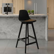 Black bar stool against a gray wall on a gray floor