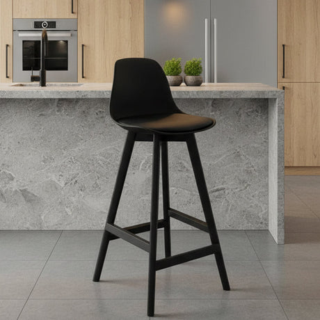 Black bar stool against a gray wall on a gray floor