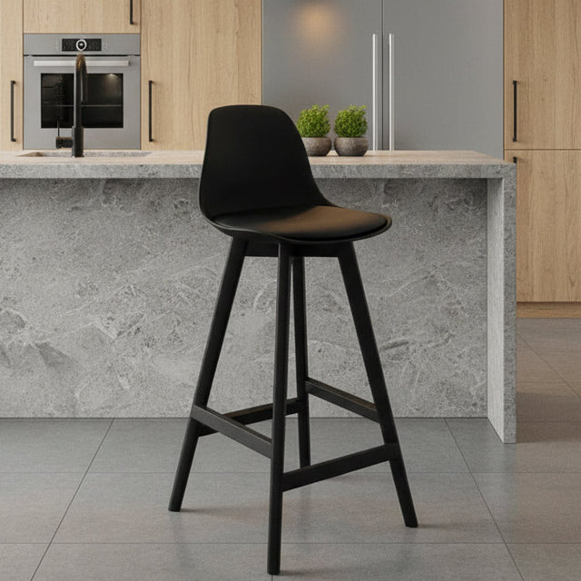 Black bar stool against a gray wall on a gray floor