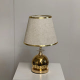 Elegant gold and beige table lamp with a spherical textured gold base and a beige-colored fabric shade.
