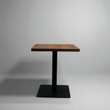 Small wooden table with a black metal base on a gray background