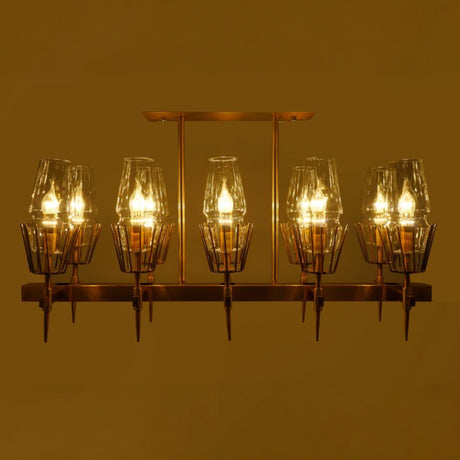 A gold-finished linear chandelier with exposed bulbs, casting a warm glow in a dimly lit setting.