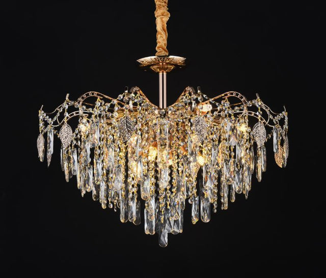 A crystal chandelier featuring a radiant gold finish and a stunning tiered design adorned with shimmering crystal prisms, set against a black background.