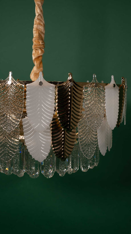A side angle of the chandelier, showing its symmetrical arrangement of glass leaves, suspended by a twisted golden chain for an elegant look.