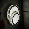  A set of three overlapping circular LED wall lights with crystal detailing, mounted on a dark wall.