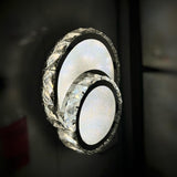  A set of three overlapping circular LED wall lights with crystal detailing, mounted on a dark wall.