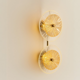 Decorative wall light fixture with gold and clear glass design on a beige wall.