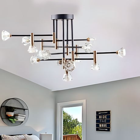 A modern black and gold chandelier with clear, sculpted glass light covers, featuring multiple branching arms in a starburst arrangement, installed on a white ceiling in a stylish living room with minimalist decor, including a round wall shelf, a cozy sofa, and a decorative sign that reads 'Ride The Wave'