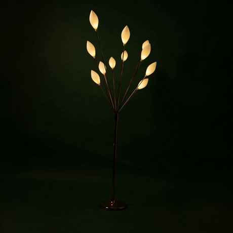 A floor lamp with multiple petal-like white plastic bulbs, shining brightly in a dark setting.