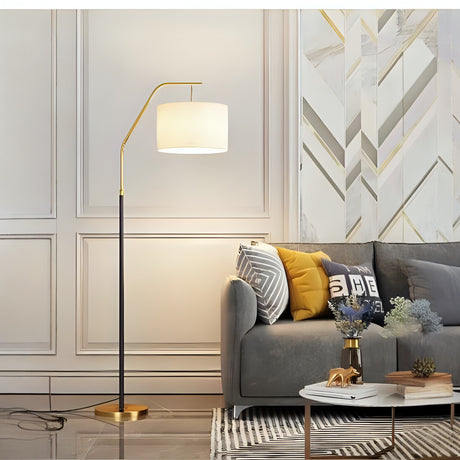 A stylish floor lamp with a black and gold stand and a beige lampshade, complimenting a luxurious living room with a gray couch and decorative pillows.