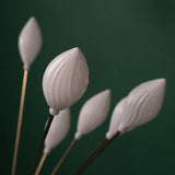  A close-up of a floor lamp with multiple white, petal-shaped plastic shades on thin metal stems, giving a floral aesthetic.