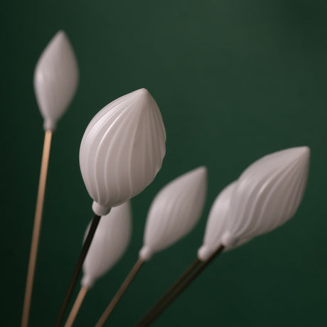  A close-up of a floor lamp with multiple white, petal-shaped plastic shades on thin metal stems, giving a floral aesthetic.