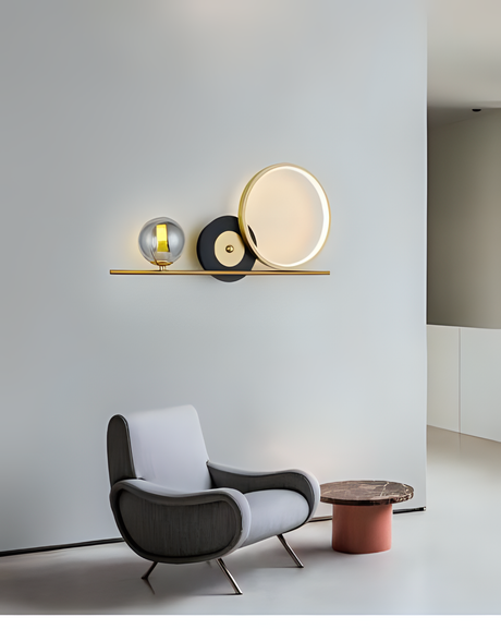 A stylish wall-mounted fixture with a gold bar and geometric elements, placed above a designer chair, complementing the minimalist decor.