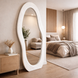 Large oval mirror in a bedroom setting with a bed and decor.