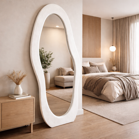 Large oval mirror in a bedroom setting with a bed and decor.