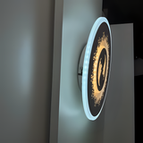 White round wall lamp featuring a small flower motif, mounted on a white wall.