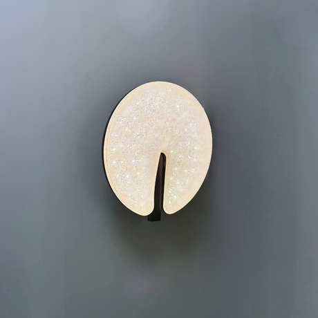 Modern circular LED wall light fixture with a sparkling textured surface and a sleek brown cut-out design, mounted on a dark-colored wall.
