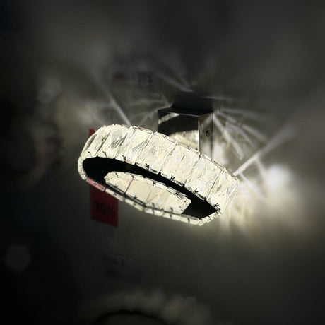 A circular crystal wall light with an elegant ring design, emitting a bright, luxurious glow.