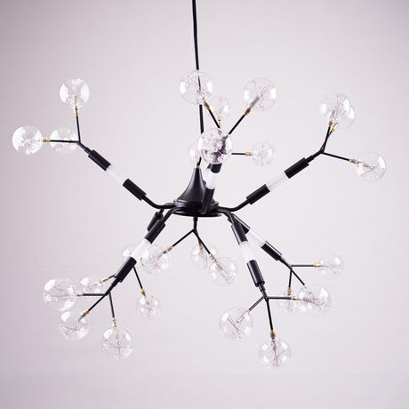 A modern, black branching chandelier with multiple exposed bulbs housed in clear, globe-shaped glass covers, resembling a molecular structure, hanging against a pale background.