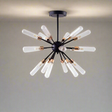 A black chandelier with long, exposed tube bulbs arranged in a off white ceiling