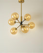 Modern chandelier with gold finish and clear glass bulbs on a neutral background
