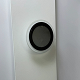 Unlit circular wall-mounted LED light with a sleek black center and white rim, blending into a minimalist white wall background.