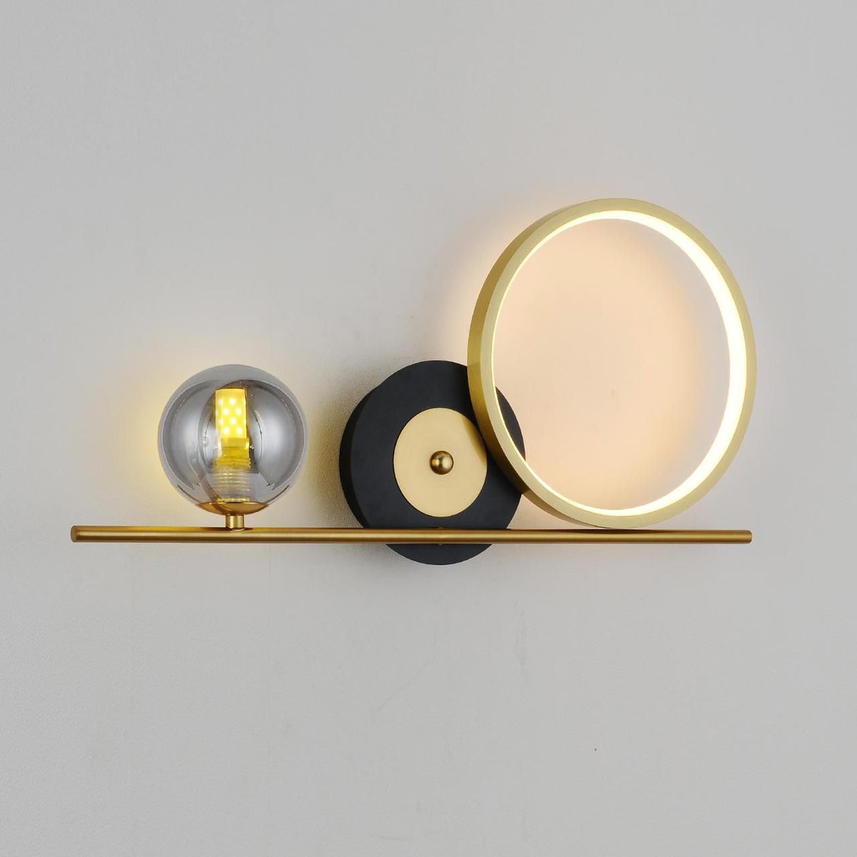 wall light  gold horizontal bar with circular elements, including a frosted LED ring and a smoked glass globe, creating a sophisticated and contemporary look.