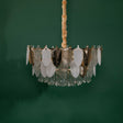 A full view of the chandelier against a green background, highlighting its circular frame adorned with alternating gold, white, and clear glass leaves.