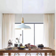A sleek white and gold pendant light with a smooth, curved shade, illuminating a wooden dining table.
