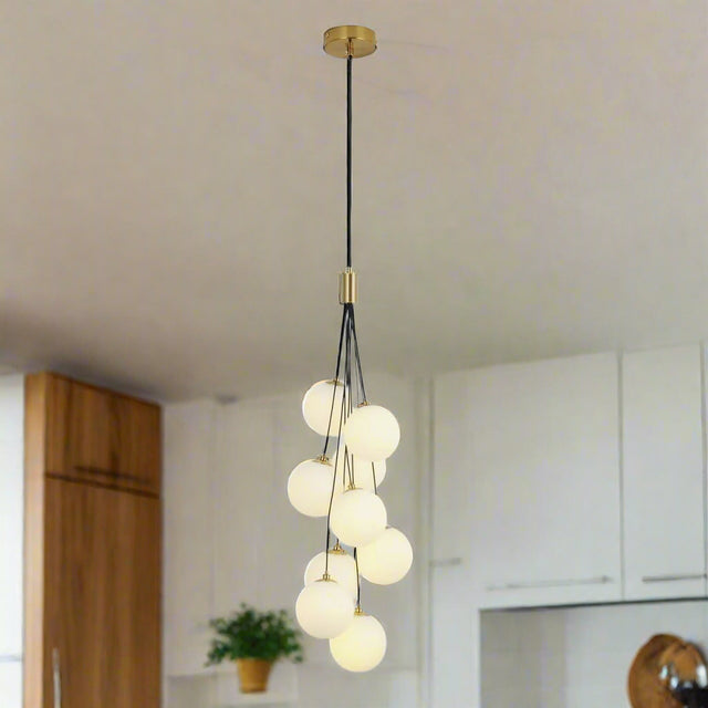  A cluster of frosted white glass globes hanging from a gold fixture, forming a cascading pendant light design.