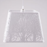 A white square-shaped pendant lampshade with intricate tree patterns cut into the metal frame.
