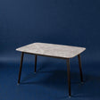 Rectangular table with marble-like top and black legs on a blue background