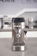 Stainless steel espresso machine on a reflective surface with blurred background