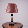 An elegant brown table lamp featuring a classic white lampshade and a sleek black-and-transparent glass base, placed on a wooden table. Equipped with an E27 LED light, it radiates a warm and sophisticated glow, enhancing the ambiance with a touch of refinement.
