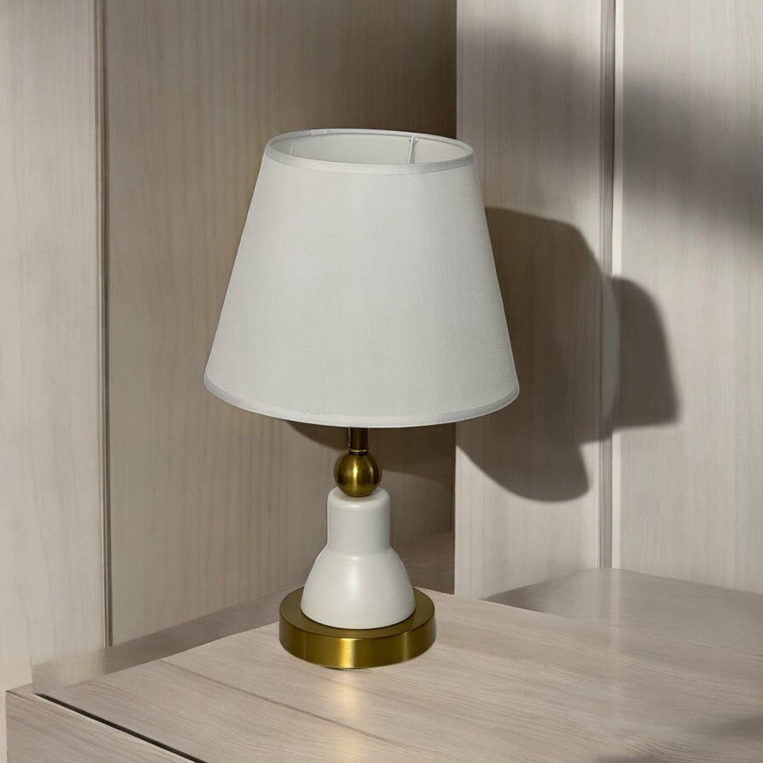 Minimalist white and gold table lamp with a sleek design and a tapered white lampshade with delicate white trim.