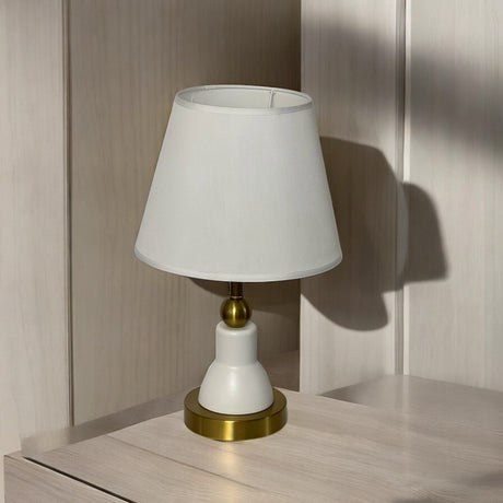 Minimalist white and gold table lamp with a sleek design and a tapered white lampshade with delicate white trim.