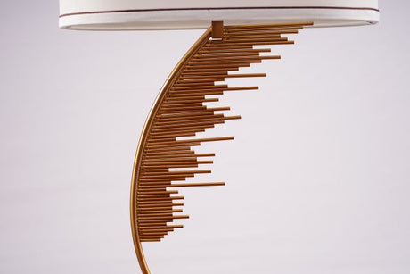 A contemporary table lamp with a gold metal base shaped like a curved staircase or an abstract wave pattern. The base is mounted on a black square platform. 
