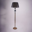 A tall, elegant floor lamp with a black lampshade, a golden stand, and black and crystal accents in the middle.