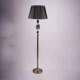A tall, elegant floor lamp with a black lampshade, a golden stand, and black and crystal accents in the middle.