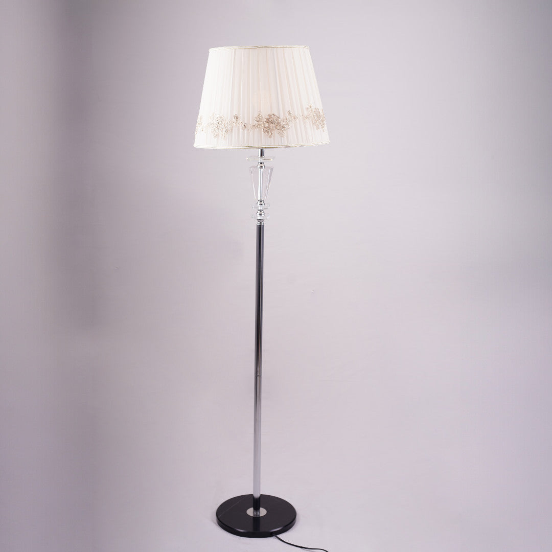 Classic floor lamp with a white embroidered shade and a slim black and silver stand, positioned against a neutral background.