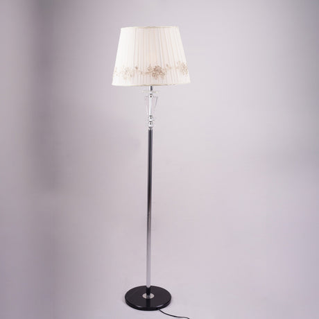 Classic floor lamp with a white embroidered shade and a slim black and silver stand, positioned against a neutral background.