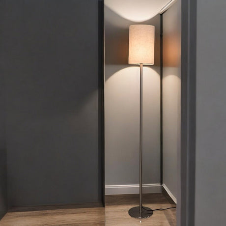 A minimalist floor lamp with a beige lampshade and a metallic stand, positioned in the corner of a room with mirrors reflecting its light.