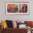 Living room with a brown sofa, colorful pillows, and a cityscape painting on the wall.
