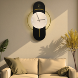 Modern wall clock on a wall above a beige sofa with green cushions.